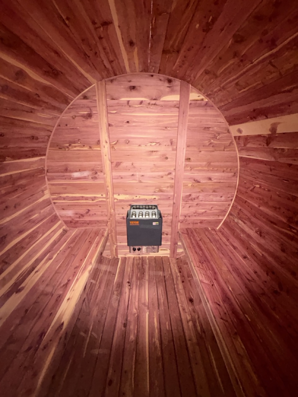Bird's-eye view looking straight down a cedar barrel sauna interior with electric sauna heater