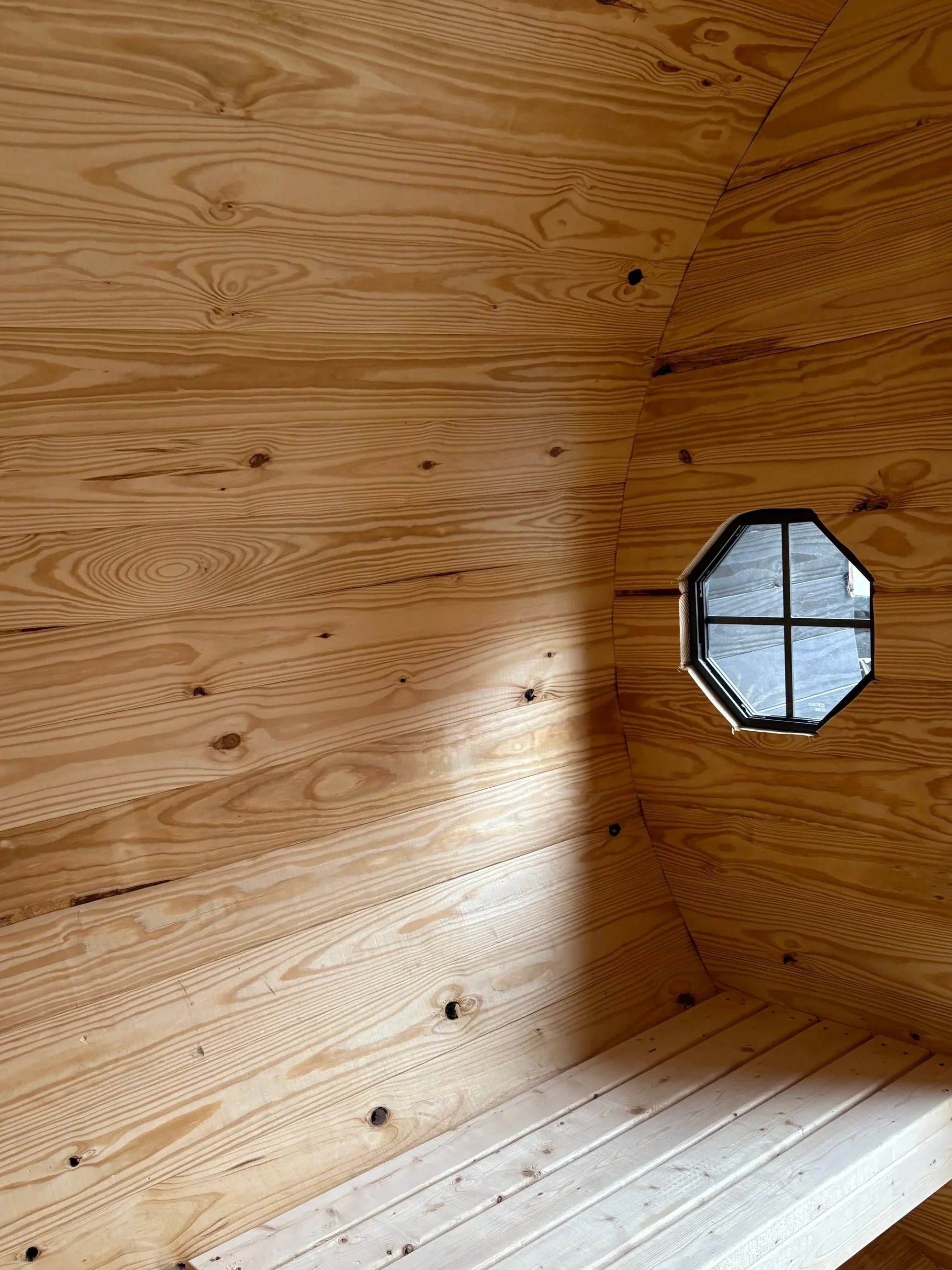 Pine wood grain and octagonal window detail inside a Cedar Ridge barrel sauna